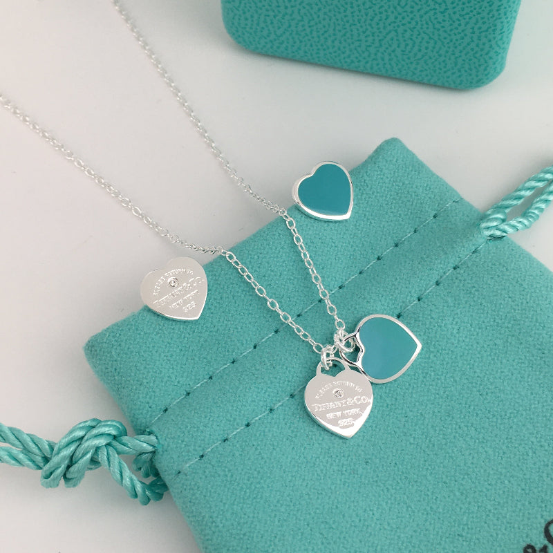 Silver heart-shaped pendant necklace on a turquoise jewelry pouch